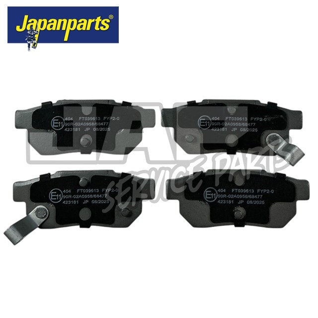 Four black Japanparts brake pads with silver metal tabs are arranged in two rows against a white background, with visible part numbers and certification markings on each pad. | Jap Service Parts - Car Parts